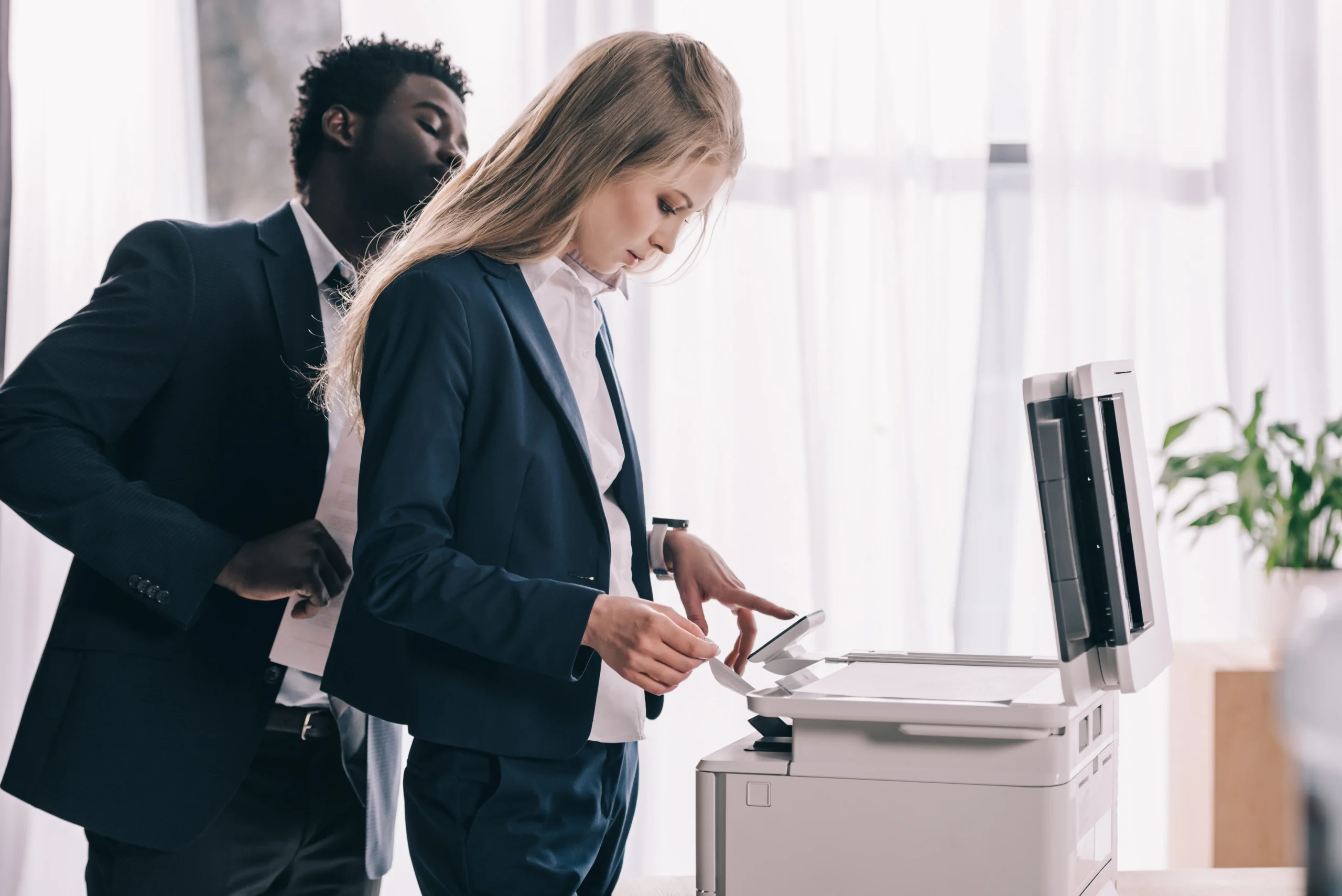 Young businesspeople using copier together at office