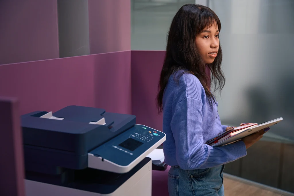 Young woman standing near copier in office